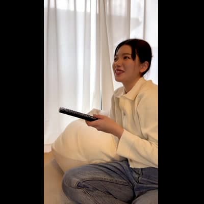 ソファでテレビを見て笑う｜リラックス風